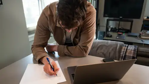 A man on the phone at his desk beside an open laptop